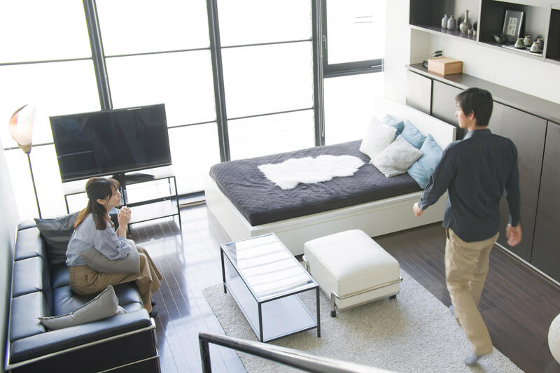 A woman on a sofa and a man walking around the room